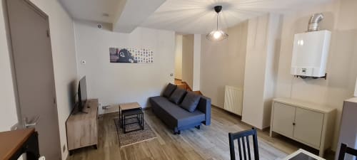 Séjour moderne à Beaune avec canapé bleu, espace repas, télévision et kitchenette