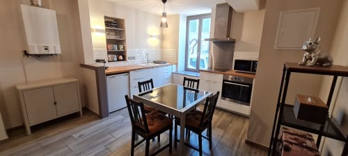 Cuisine-salle à manger moderne à Beaune avec placards blancs, table noire et électroménagers en inox.