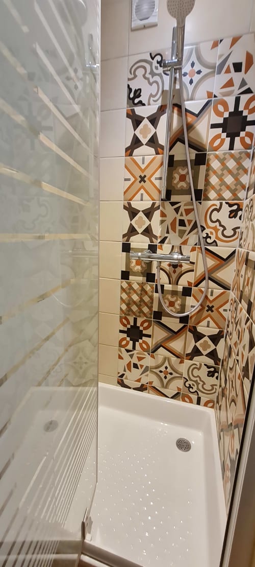 Douche moderne avec carrelage aux motifs marocains décorés en orange, marron et noir à la Conciergerie Des Climats,