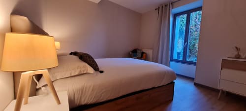 Chambre contemporaine à la Conciergerie Des Climats à Beaune avec lit, lampe de chevet, portes vitrées donnant sur balcon et vues sur la ville