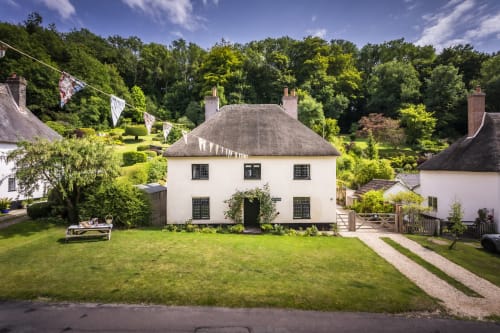 Three Little Pigs cottage hotel in Blandford Forum with thatched roof, white walls, and manicured lawns