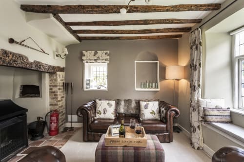 Cozy living room at Three Little Pigs hotel in Blandford Forum with leather sofa, exposed beams, fireplace, and period décor.