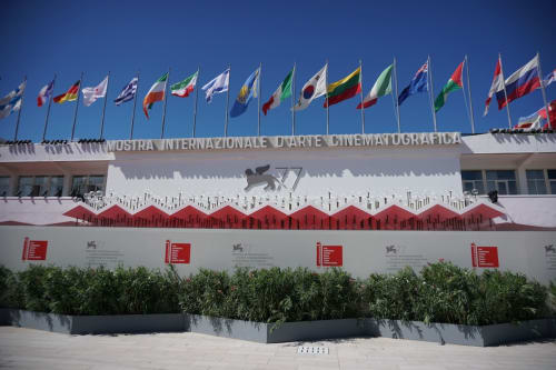 Venice Film Festival palazzo with international flags and red tent structures on beach, Cannaregio area