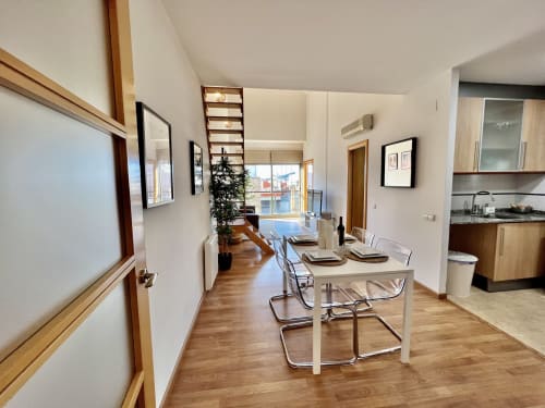 Zona de comedor moderno de J&A Apartments en Terrassa con cocina, suelo de madera y vistas a la ciudad