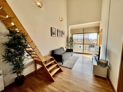 Moderno loft en J&A Apartments en Terrassa con escaleras de madera, sofá y vistas a la ciudad