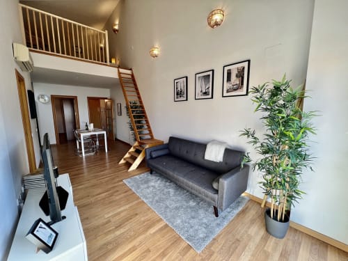 Loft moderno en Terrassa con sofá, altillo, escaleras de madera, plantas y decoración contemporánea