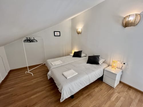 Dormitorio moderno en Apartamentos J&A en Terrassa con cama queen, mesita de noche blanca, suelos de madera y decoración minimalista