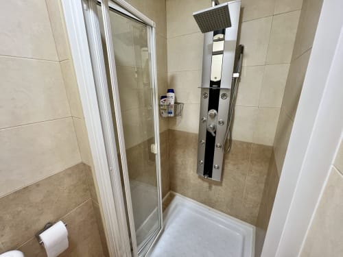 Moderno baño con ducha en J&A Apartments en Terrassa con alcachofa de lluvia, jets de agua y puerta de cristal