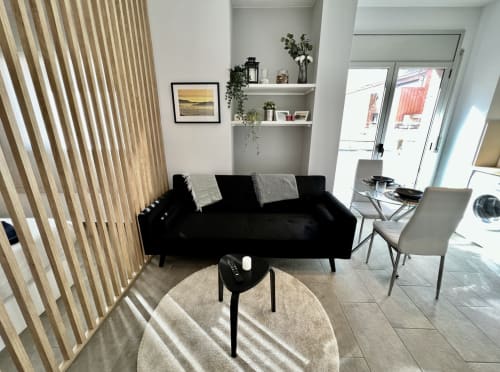 Sala de estar moderna en los Apartamentos J&A de Terrassa con sofá negro, alfombra redonda y estanterías