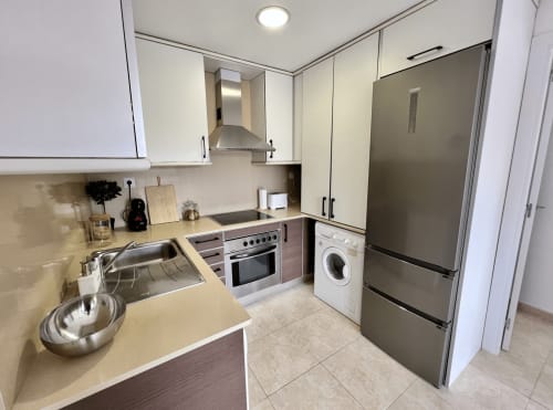 Cocina moderna en Apartamentos J&A en Terrassa con electrodomésticos de acero inoxidable, gabinetes blancos y lavadora