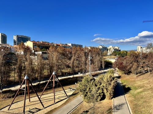 Área de parque con equipos de juegos y árboles otoñales en los Apartamentos J&A en Terrassa, España