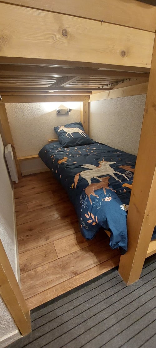 Petite alcôve avec lit superposé douillet dans l'appartement CMD Méribel Le Pralin, parure de lit bleu marine aux motifs de cerfs et structure en bois