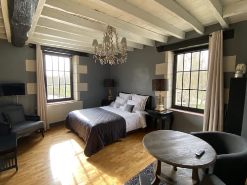 Chambre élégante au Moulin De La Chevrière avec poutres apparentes, lustre et deux grandes fenêtres