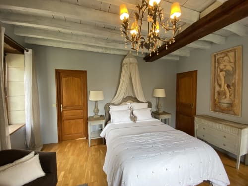 Chambre élégante du Moulin De La Chevrière à Saché, avec lit à baldaquin, lustre en cristal et décor d'époque