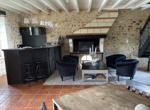 Salon rustique en pierre avec bar noir, cheminée et sièges bleu marine au Moulin De La Chevrière à Saché