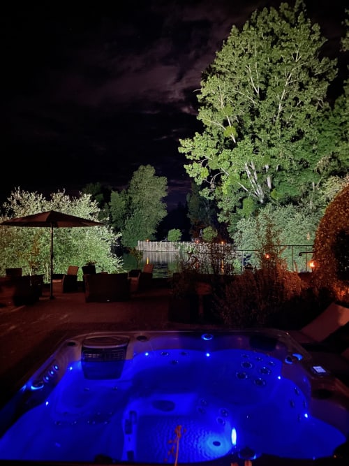 Bain à remous illuminé aux lumières bleues au Moulin De La Chevrière à Saché, France, surplombant les jardins éclairés la nuit