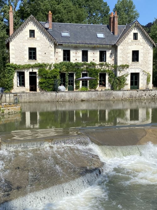Moulin De La Chevrière, gîte au bord de l'eau à Saché, façade en pierre blanche et terrasse couverte de lierre