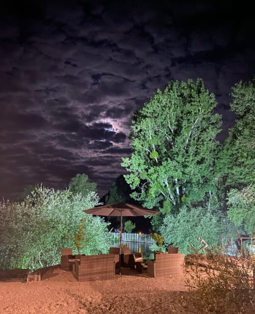 Espace de détente nocturne au Moulin De La Chevrière avec parasol et éclairage par lanterne à Saché