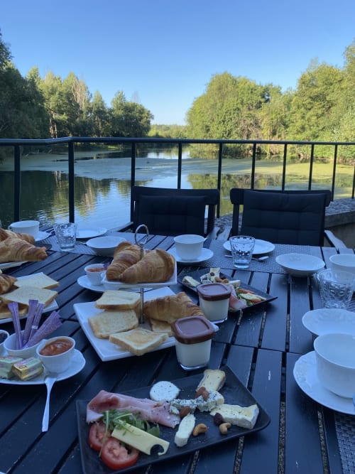 Petit-déjeuner au bord de la rivière au Moulin De La Chevrière avec viennoiseries, charcuterie et vue sur l'eau