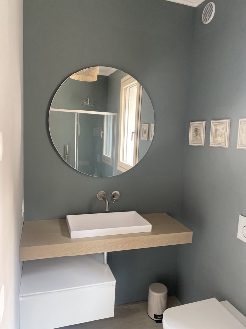 Modern bathroom at Verdolivo B&B in Sale Marasino with round mirror, wooden vanity, and white vessel sink