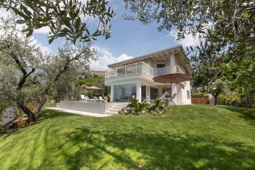 Modern white villa at Verdolivo B&B in Sale Marasino with manicured lawn, olive trees, and furnished terrace
