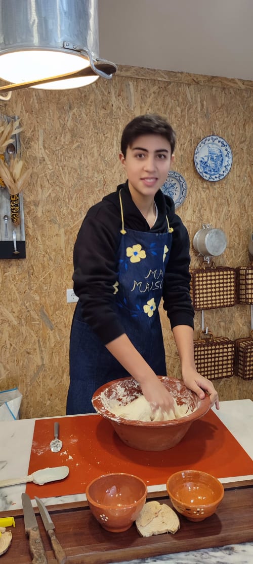 Young person preparing dough in rustic kitchen at Kindnessmoon guesthouse, Obidos Portugal