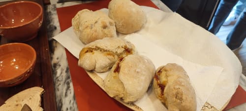 Freshly baked bread rolls on white napkin with terracotta bowls at Kindnessmoon Alojamentos in Obidos, Portugal