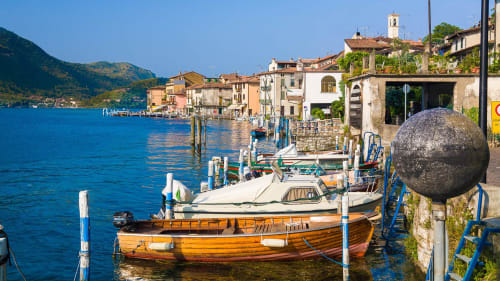 Farbenfrohe Fischerboote vertäut in türkisem Wasser des Iseo-Sees nahe der Unterkunft Verdolivo B&B in Sale Marasino, Italien