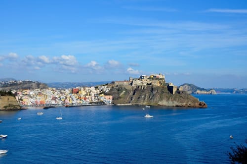 Affascinante lungomare colorato di Procida con il Castello Aragonese che domina la baia, Italia. Ubicazione Palazzo Porta.