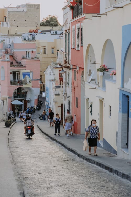 Via colorata di Procida con edifici pastello, archi e abitanti passeggiare vicino al Palazzo Porta B&B