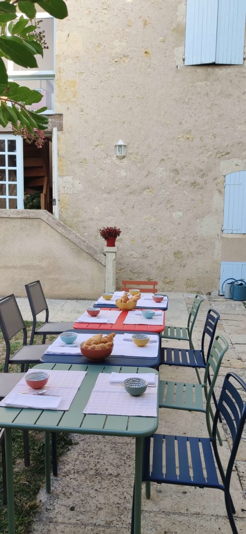 Terrasse des petits-déjeuners du Rêve d’Alice avec tables dressées contre la façade en pierre