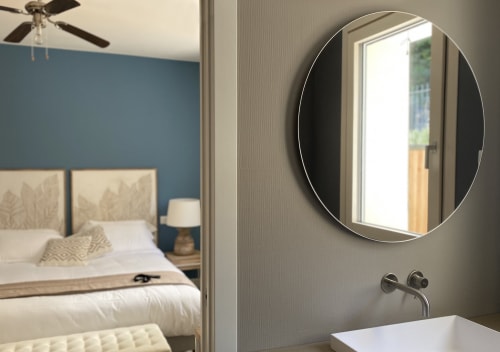 Modernes Badezimmer im Verdolivo B&B mit rundem Spiegel, eleganten Armaturen und Blick ins blauakzentuiertes Schlafzimmer, Sale Marasino