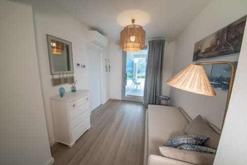 Modernes Schlafzimmer im Verdolivo B&B in Sale Marasino mit Rattan-Hängeleuchte, weißer Kommode und Blick auf die Terrasse
