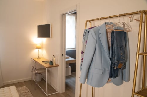 Hotelzimmer im Verdolivo B&B mit Kleiderständer, Schreibtisch, Lampe und offener Tür zum Schlafzimmer in Sale Marasino