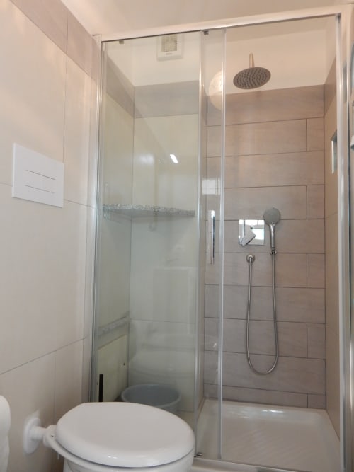 Modern bathroom in Azzurra Room at B&B Eleonora D'Arborea, Posada, featuring walk-in shower with rainfall showerhead and