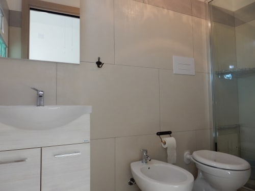 Modern bathroom in Sarda Room at B&B Eleonora D'Arborea, Posada, featuring sink, bidet, toilet, and shower enclosure