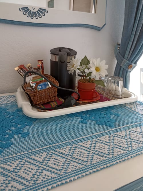 Welcoming tray in Azzurra Room at B&B Eleonora D'Arborea features coffee maker, snacks, fresh daisies, and blue coastal decor