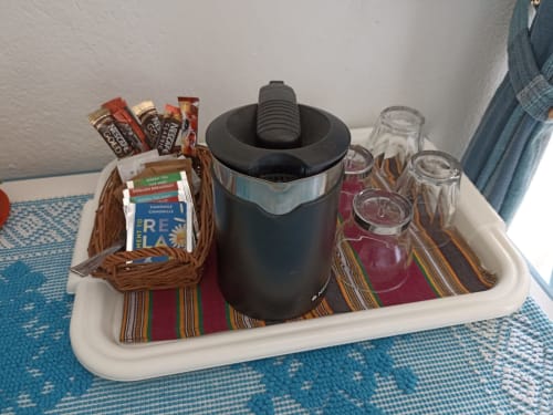 Welcome tray in Sarda Room with kettle, coffee, tea, snacks, glasses and colorful striped cloth at B&B Eleonora D'Arborea,