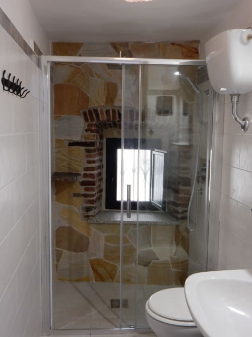 Modern shower enclosure in Eleonora Room at B&B Eleonora D'Arborea, Posada with glass doors and natural stone tiles