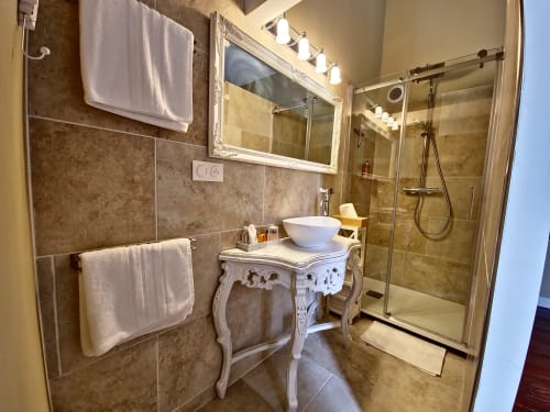 Salle de bains élégante du Manoir Le Coutureau avec vasque blanche, coiffeuse ornementée, douche à l'italienne et porte-serviettes chauffant