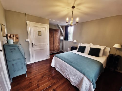 Chambre élégante au Manoir Le Coutureau à Rouffignac de Sigoules avec lit queen-size, commode bleue, parquet et lustre
