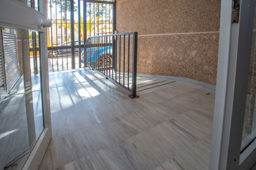 Balcón moderno con piso de madera, barandilla metálica y paredes de corcho con vistas a Puerto Santa María