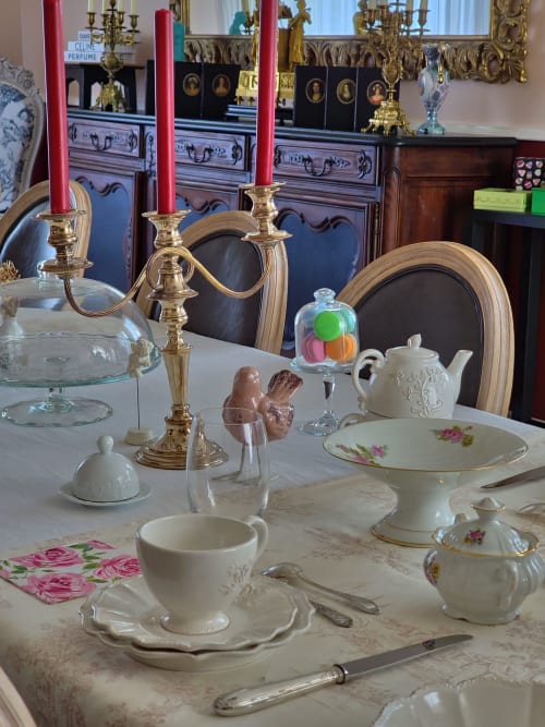 Table élégante du Manoir Le Coutureau avec porcelaine fine, candélabre en laiton et services à thé floral à Rouffignac