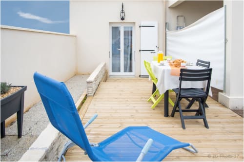 Terrasse ensoleillée du gîte Le Pirate Benèze à Trizay avec table à manger, transat bleu et vue sur le jardin