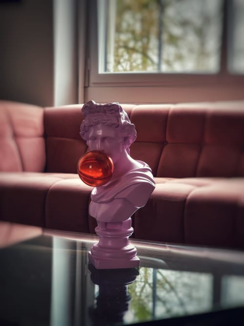 Buste sculpture violet avec sphère rouge sur table en verre près du canapé bordeaux au Manoir Le Coutureau B&B à Rouffignac de Sigoules