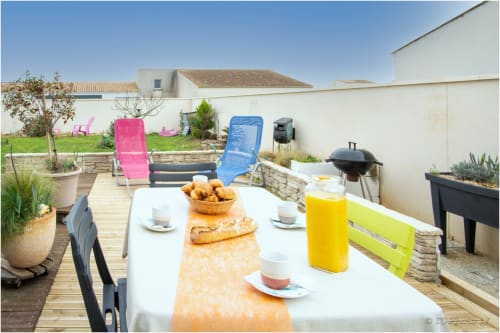Terrasse extérieure du Pirate Benèze à Trizay avec table de petit-déjeuner, transats colorés et vue sur le jardin