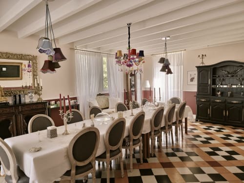 Élégante salle à manger du Manoir Le Coutureau avec nappe blanche, chaises ornées, lustres et carrelage à damier
