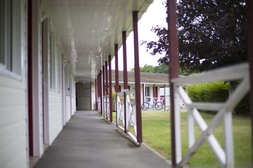 Galerie couverte de l'Hôtel Mape à Dampierre-en-Burly avec balustrades blanches, colonnes bordeaux et jardins paysagés