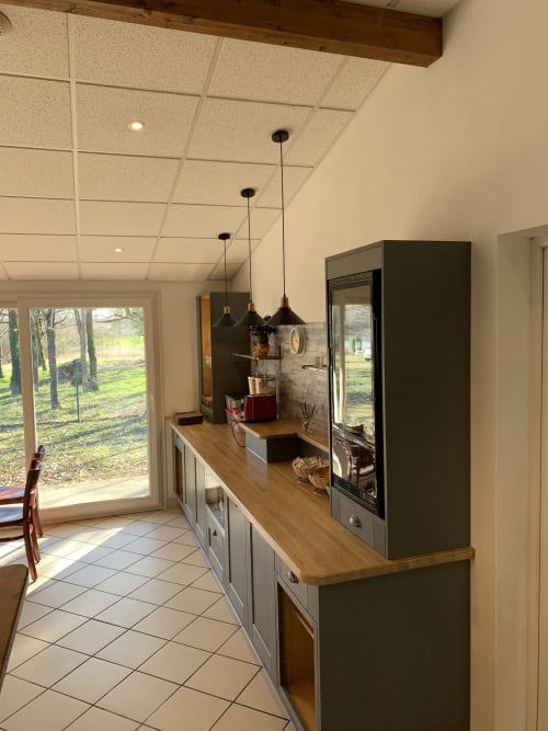Cuisine moderne de l'hôtel Mape à Dampierre-en-Burly avec plan de travail en bois, suspensions noires et vue sur le jardin