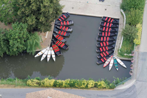 Vue aérienne spectaculaire depuis une montgolfière d'un ponton. On y voit les barques traditionnelles du Marais Poitevin amarrées au bord de l'eau, une expérience unique proposée à nos hôtes. 